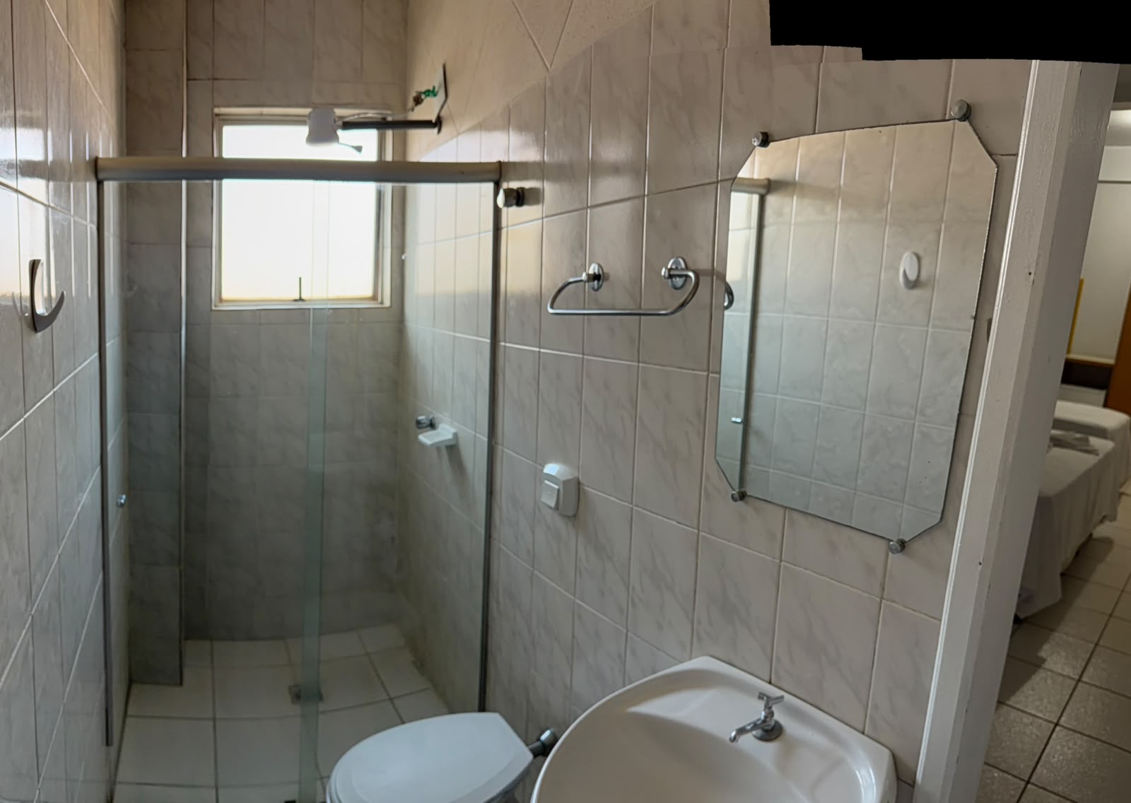 Banheiro privativo do Hotel Mello com box de vidro e espelho